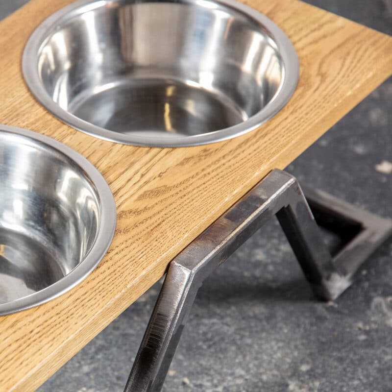 Zbliżenie dębowego stojaka z miskami dla psów z drewna i stali IDA w stylu Loft.
